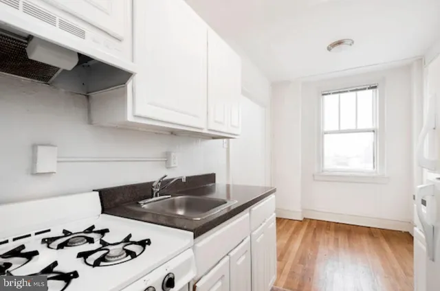 a kitchen with cabinets a stove and white stainless steel appliances