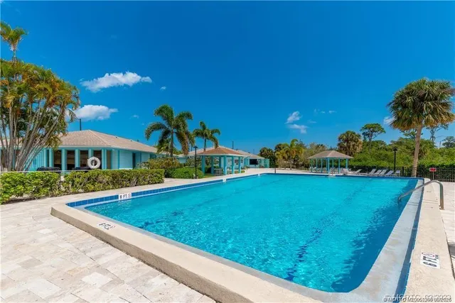 a living room with stainless steel appliances kitchen island a table and chairs in it