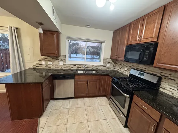 a kitchen with stainless steel appliances granite countertop wooden cabinets a stove top oven a sink and dishwasher