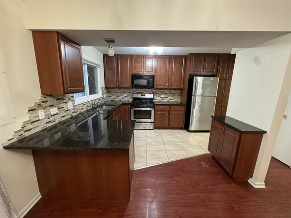 a kitchen with stainless steel appliances granite countertop a stove a sink a refrigerator and a microwave