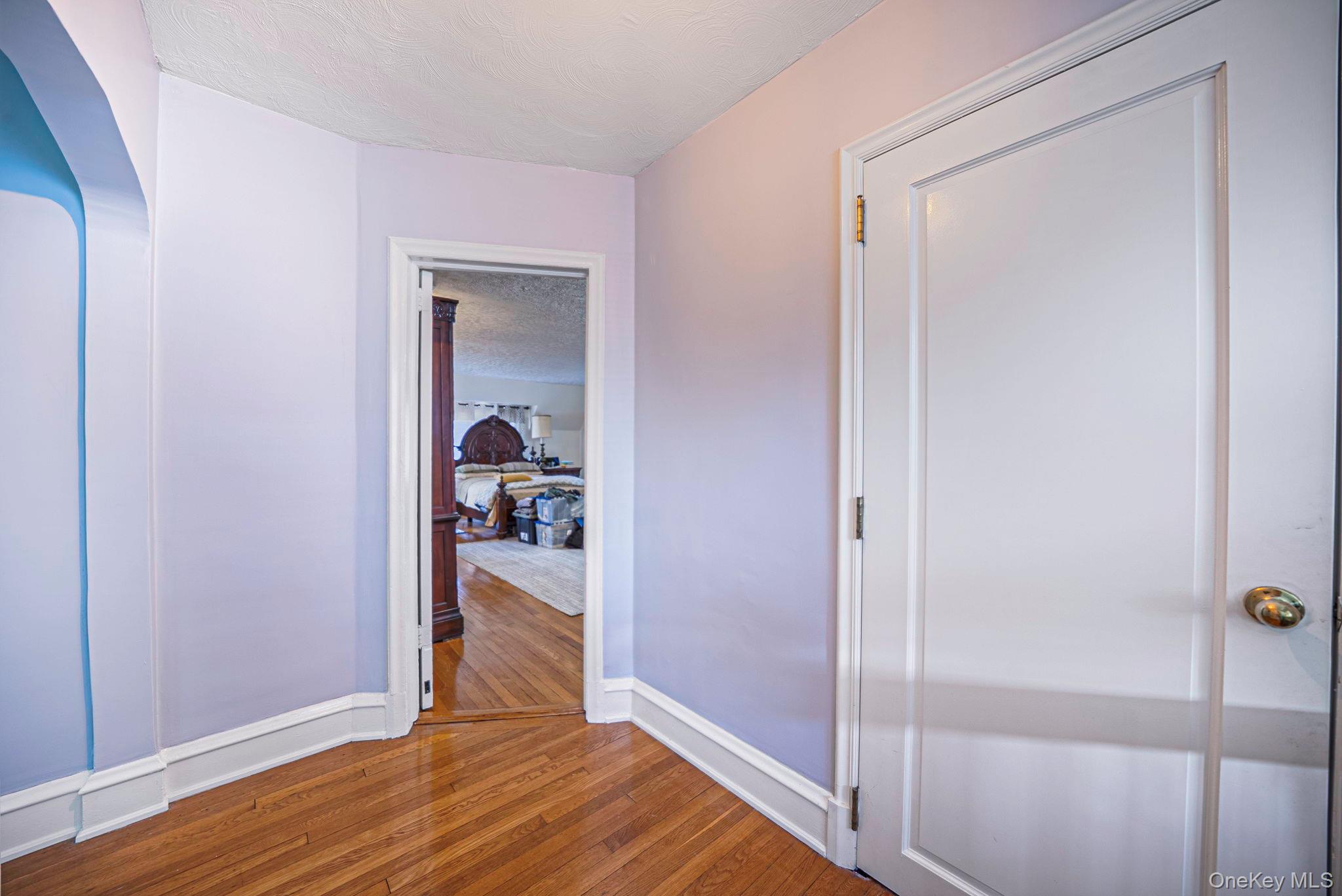 18240 Avon Road Queens, NY 11432 - Photo 15 of 30 Hardwood flooring with a diagonal pattern, white trim work, and a white interior door with brass hardware
