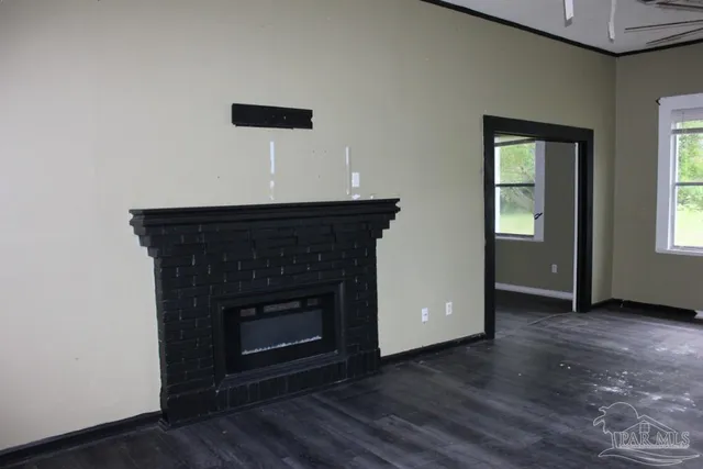 an empty room with wooden floor a fireplace and a window