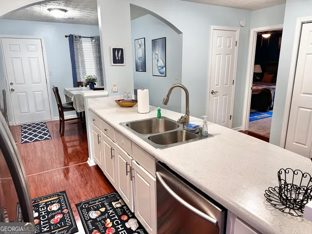 a kitchen with stainless steel appliances a sink a stove a refrigerator a dining table and chairs