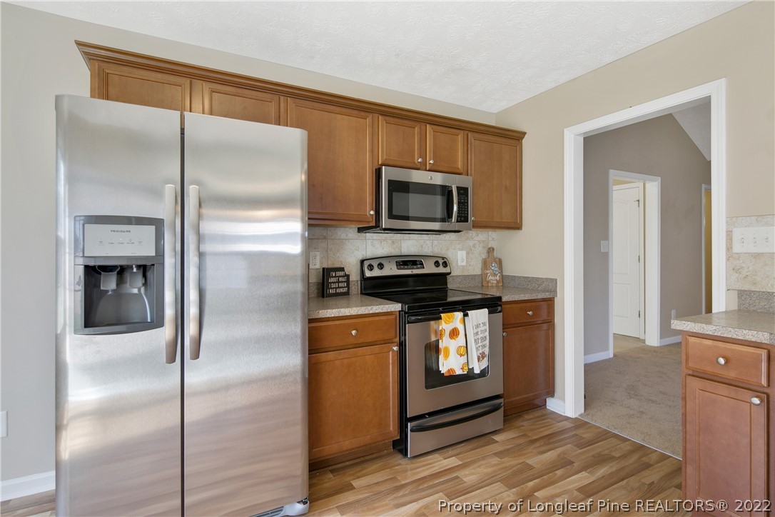 654 Hogart Street Raeford, NC 28376 - Photo 19 of 35 a kitchen with stainless steel appliances granite countertop a refrigerator a stove and a sink with wooden floor