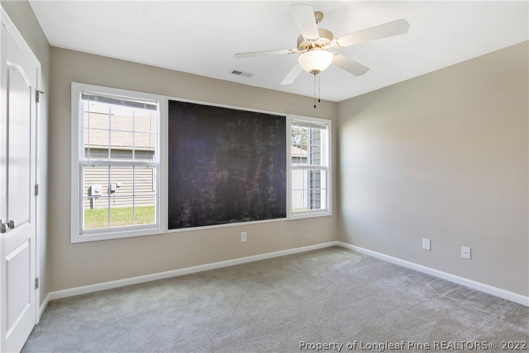 654 Hogart Street Raeford, NC 28376 - Photo 30 of 35 an empty room with windows and chandelier fan