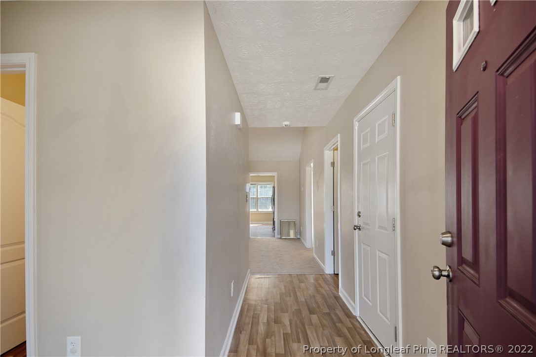 654 Hogart Street Raeford, NC 28376 - Photo 5 of 35 a view of a hallway with wooden floor and a bathroom