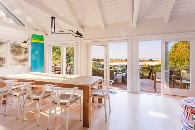 a living room with furniture a rug kitchen view and a window