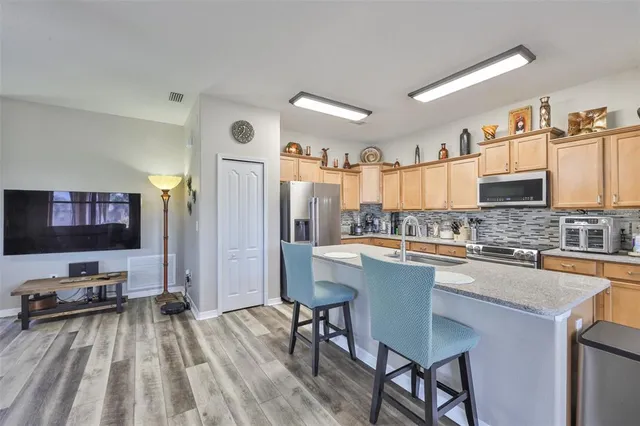 a kitchen with stainless steel appliances granite countertop a stove top oven a sink dishwasher a dining table and chairs with wooden floor