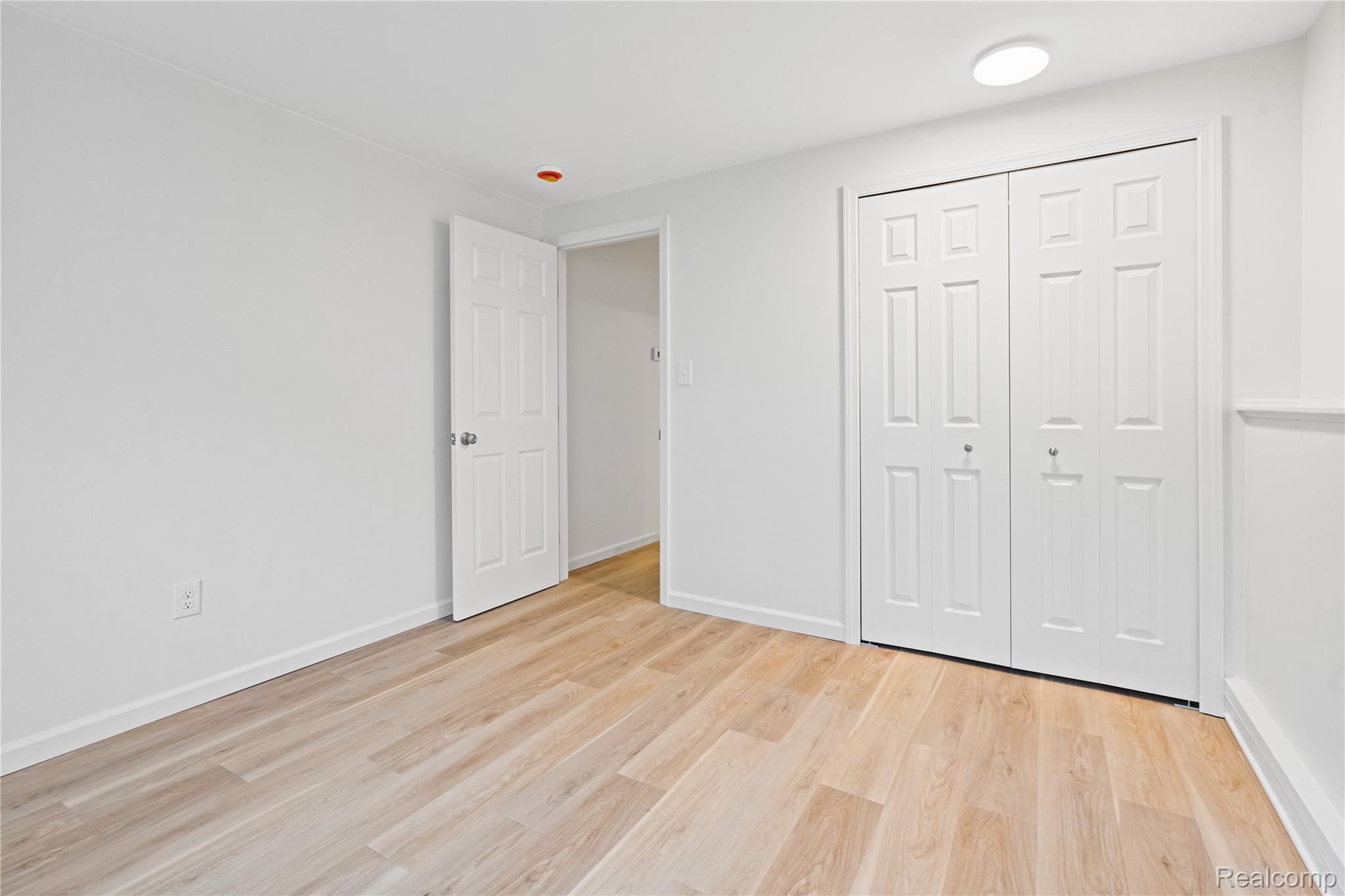8240 Hampton Road Grosse Ile, MI 48138 - Photo 27 of 33 Light wood-finish flooring, white paneled doors, and a flush-mount ceiling light fixture