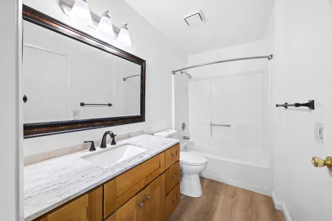 a bathroom with a granite countertop sink a toilet a mirror and shower