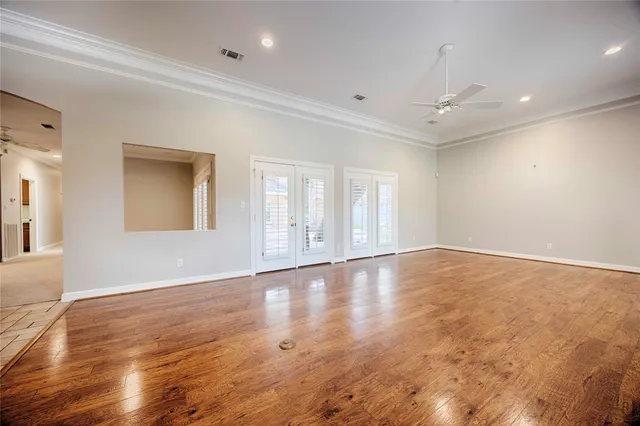 an empty room with wooden floor and windows