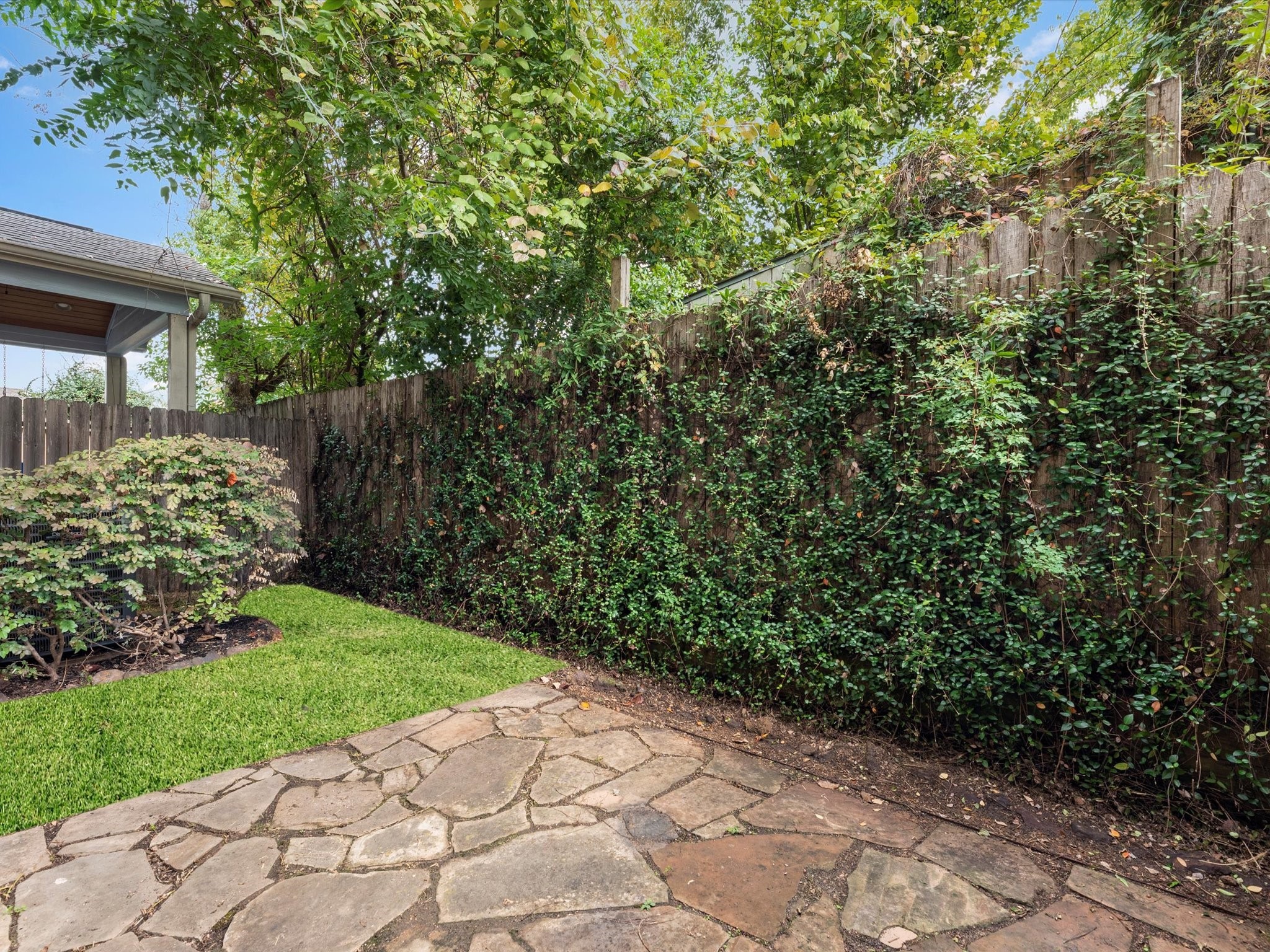 1506 Nashua Street Houston, TX 77008 - Photo 2 of 26 A sneak peak of the backyard with stone patio. NOTE: The back fence was replaced in 2024 (this is a photo of the previous fence).