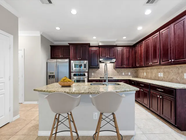 a kitchen with kitchen island granite countertop wooden cabinets a stove a sink and a refrigerator
