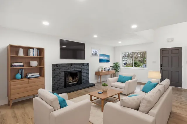 a view of a livingroom with wooden floor staircase and a kitchen