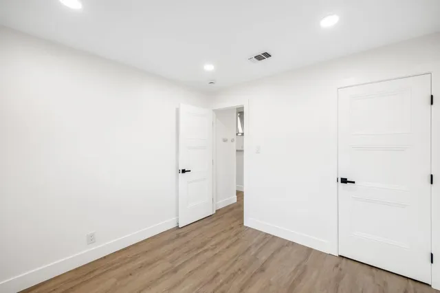 an empty room with wooden floor and a bathroom