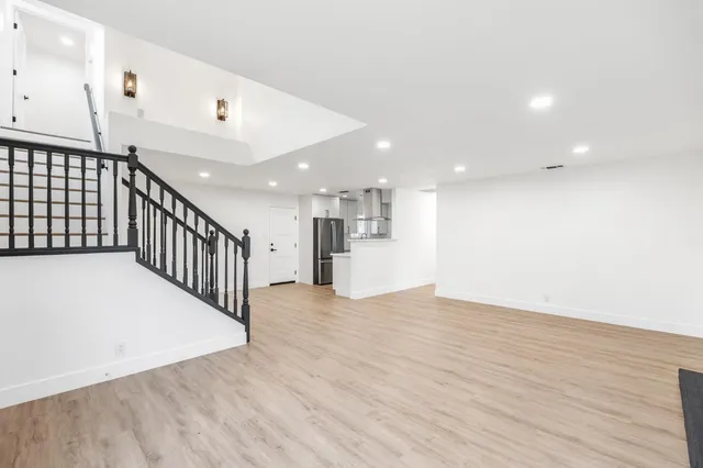 a view of an empty room with wooden floor and stairs