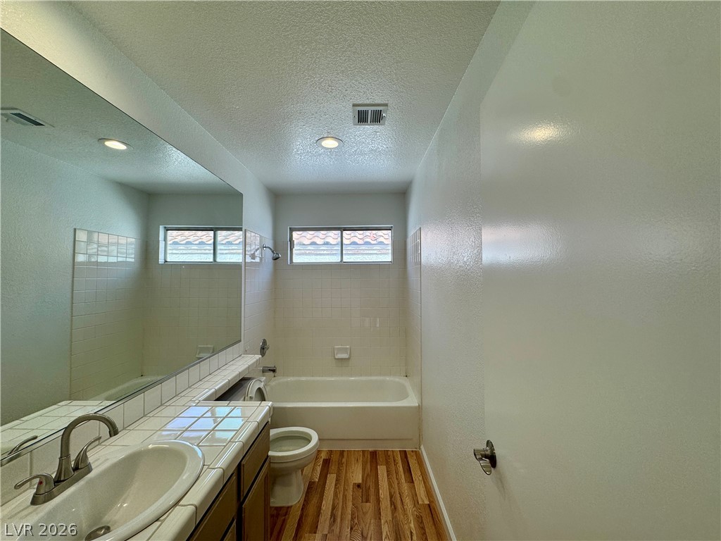 73 Sea Holly Way Henderson, NV 89074 - Photo 56 of 59 Full bath featuring vanity, light wood-style flooring, a textured ceiling, a textured wall, and bathing tub / shower combination