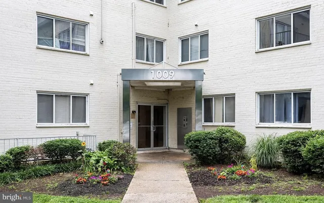 a view of a brick house with lots of windows and flower plants