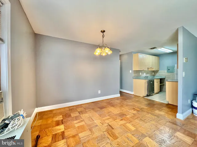 a view of an empty room with kitchen and a window