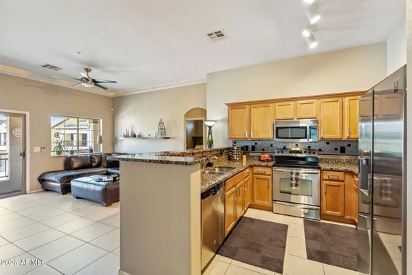 a kitchen with stainless steel appliances kitchen island granite countertop a stove top oven a sink dishwasher a dining table and chairs with wooden floor