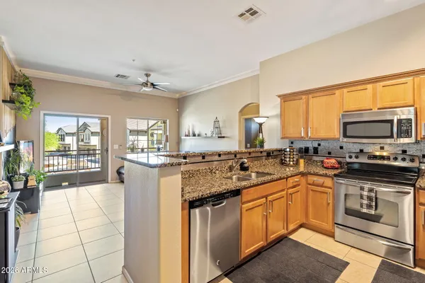 a kitchen with stainless steel appliances granite countertop a stove top oven a sink dishwasher a dining table and chairs with wooden floor