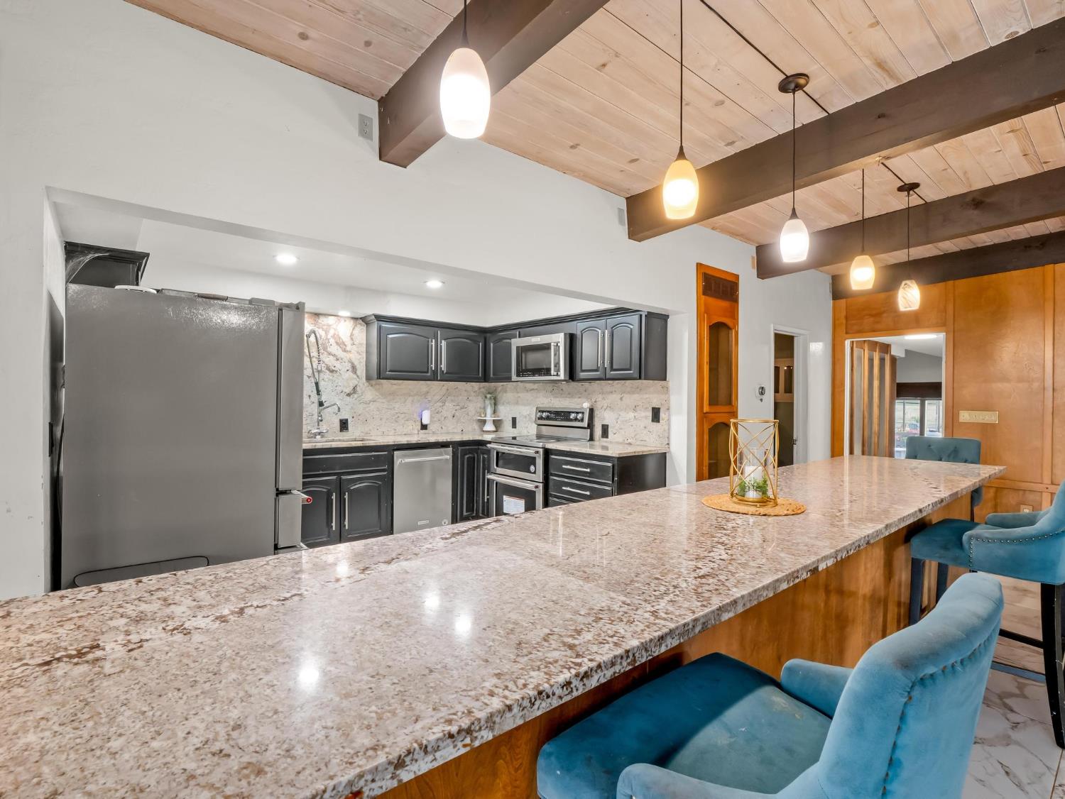 31204 Sierra Drive Exeter, CA 93221 - Photo 19 of 76 a kitchen with stainless steel appliances kitchen island granite countertop a table chairs in it and wooden floors