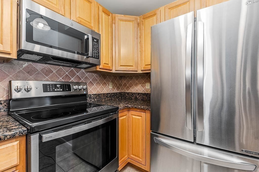 989 East Street, Unit 402 Dedham, MA 02026 - Photo 13 of 28 a kitchen with stainless steel appliances granite countertop a stove microwave and refrigerator