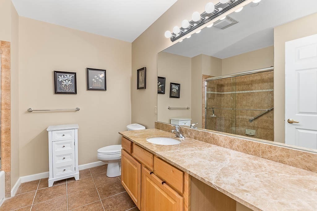 989 East Street, Unit 402 Dedham, MA 02026 - Photo 17 of 28 a bathroom with a granite countertop sink mirror vanity and toilet