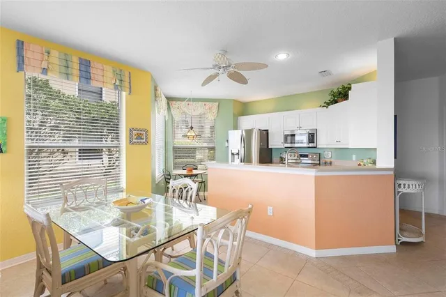 a dining room with stainless steel appliances kitchen island granite countertop a table chairs and a refrigerator