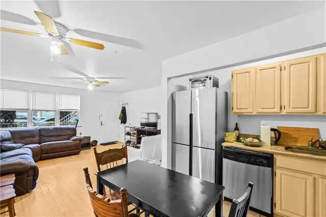 a kitchen with stainless steel appliances granite countertop a refrigerator a stove a sink dishwasher a dining table and chairs with wooden floor