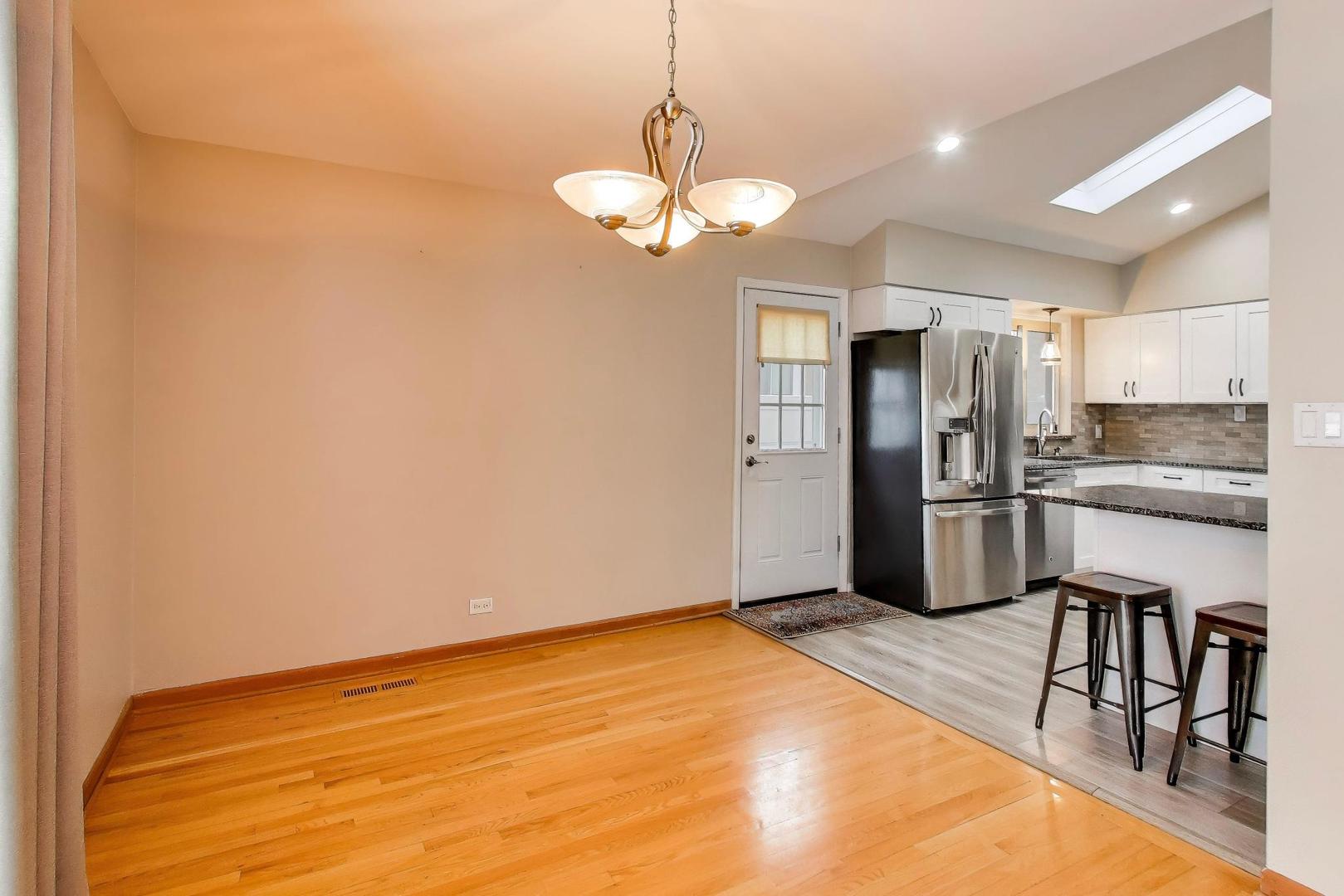 9416 Oliphant Avenue Morton Grove, IL 60053 - Photo 4 of 27 a kitchen with stainless steel appliances granite countertop a refrigerator a sink dishwasher a stove and a dining table with wooden floor