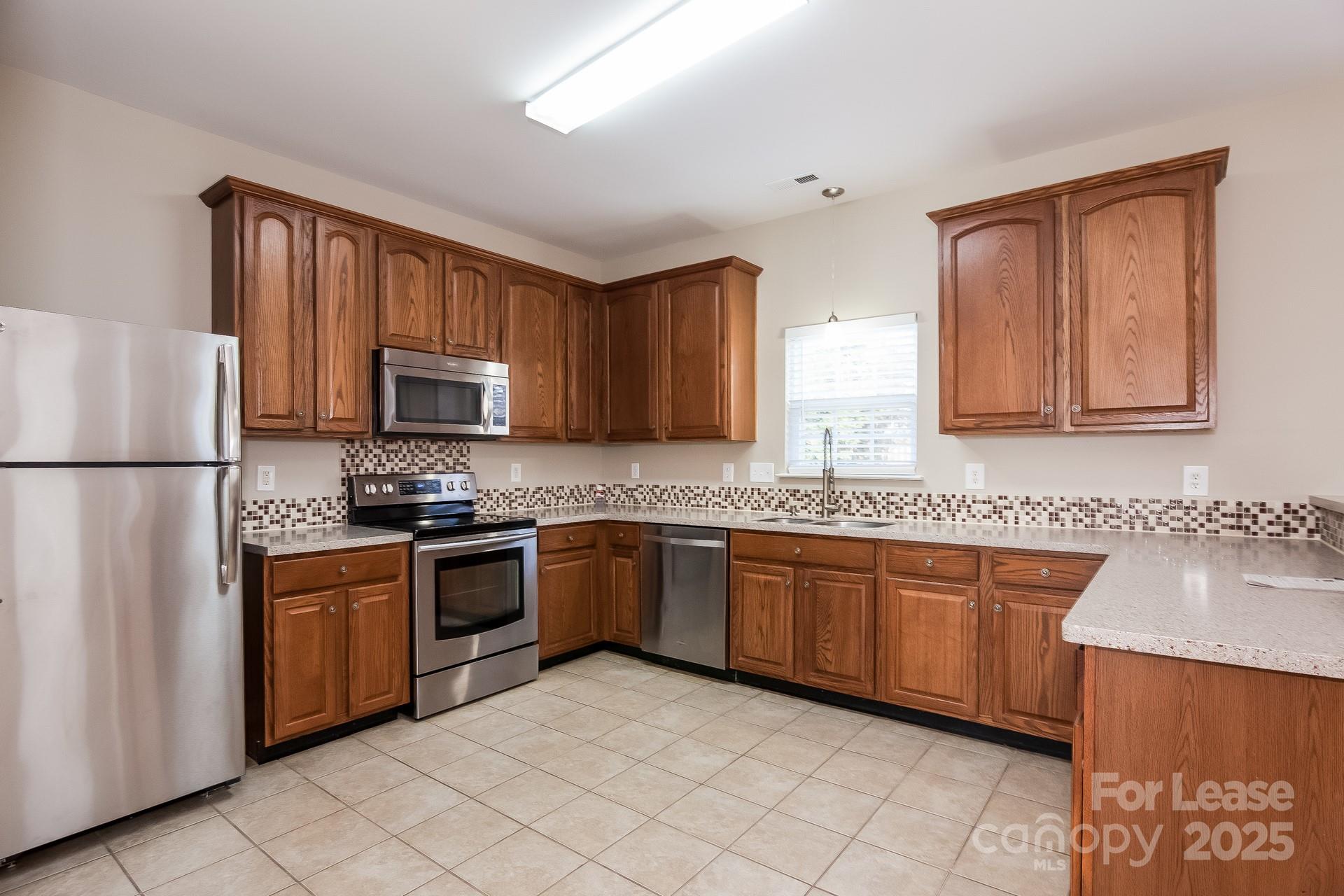 10209 Fairbourne Court Charlotte, NC 28269 - Photo 4 of 15 a kitchen with stainless steel appliances granite countertop a stove top oven a sink dishwasher and a refrigerator with wooden cabinets