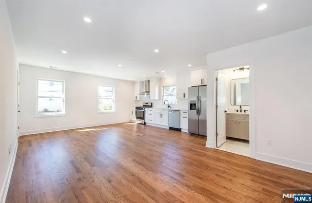 a view of a big room with wooden floor and windows