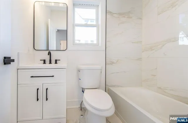 a bathroom with a toilet sink vanity tub and mirror