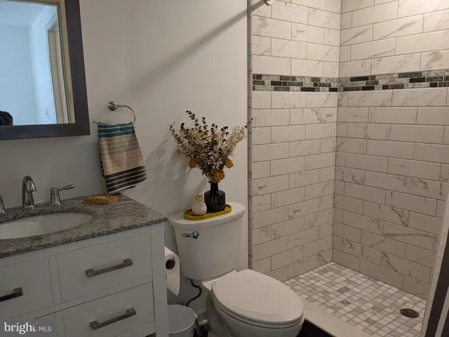 a bathroom with a granite countertop toilet sink and mirror