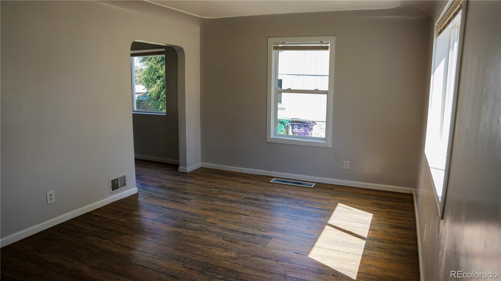 909 Meade Street Denver, CO 80204 - Photo 3 of 15 an empty room with wooden floor and windows