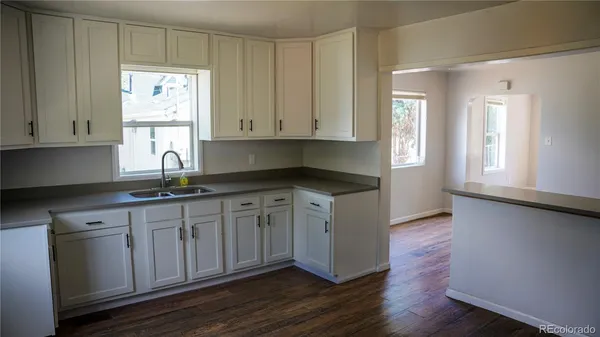 a kitchen with granite countertop white cabinets white appliances and a window