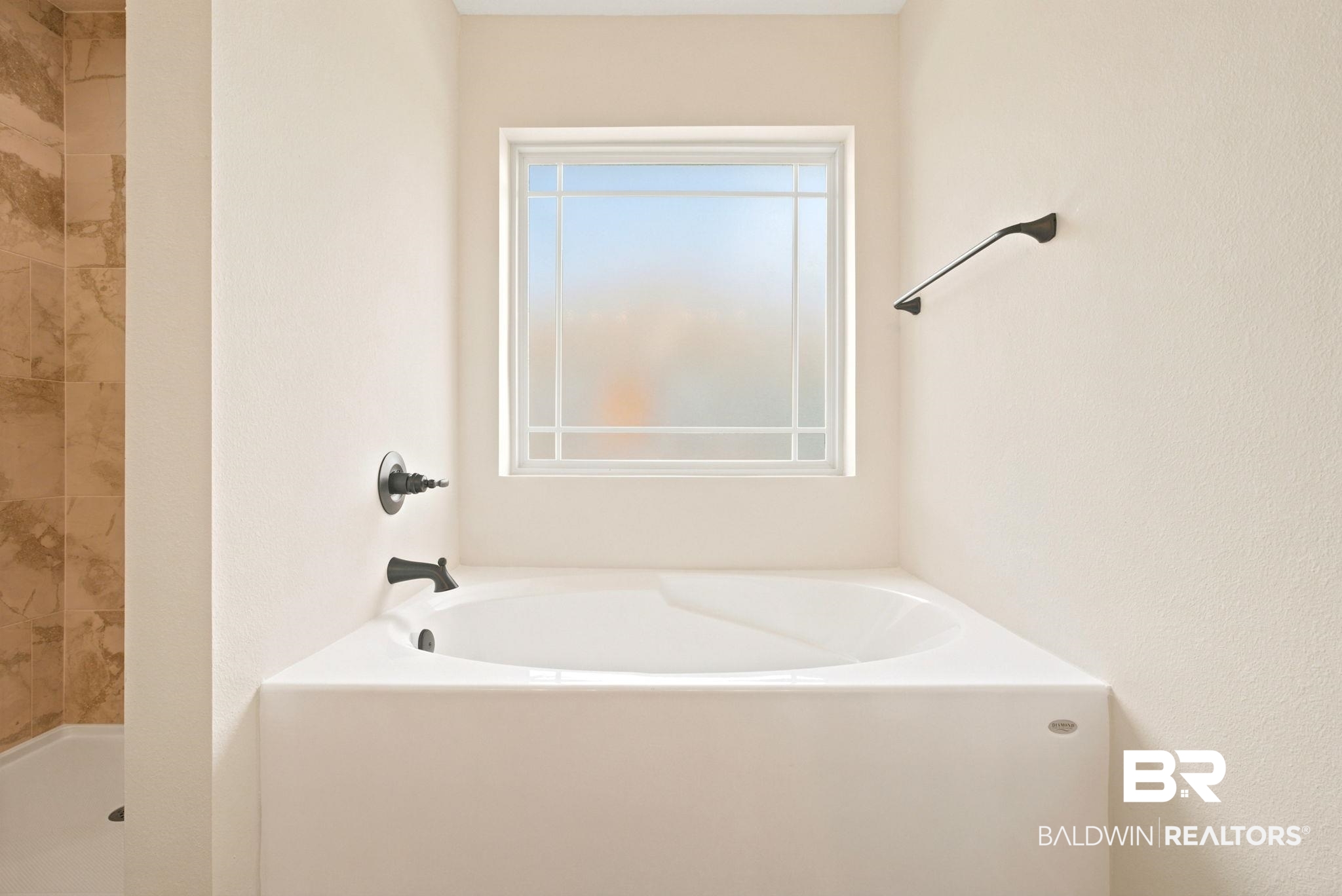32656 Arbor Ridge Circle Lillian, AL 36549 - Photo 18 of 56 White corner soaking tub with dark-finish fixtures, complemented by a frosted window with grid detailing
