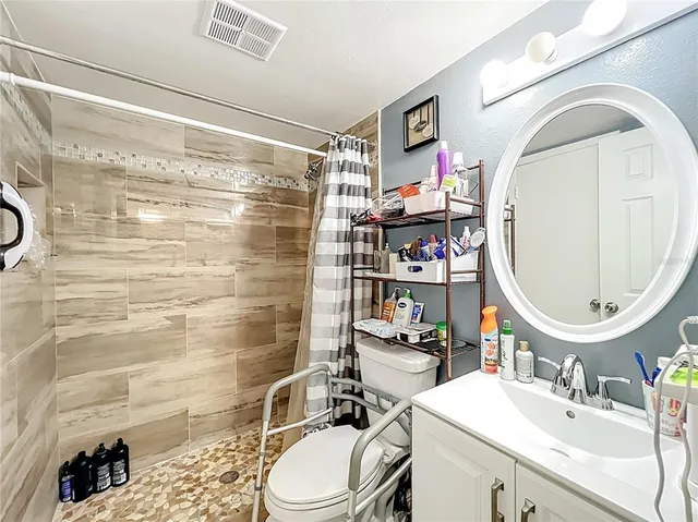 a bathroom with a sink a toilet a mirror and shower