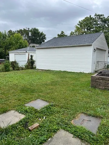 a view of a backyard with lawn chairs under an umbrella