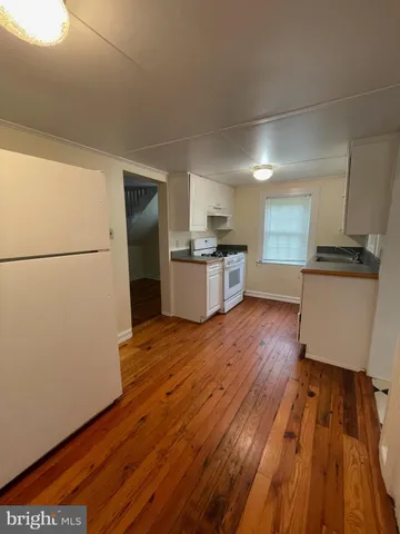 a kitchen with granite countertop wooden floors and white stainless steel appliances