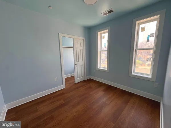 an empty room with wooden floor and windows