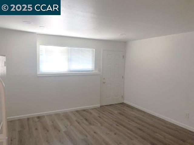 527 Vaqueros Avenue, Unit C Rodeo, CA 94572 - Photo 4 of 9 an empty room with wooden floor and windows