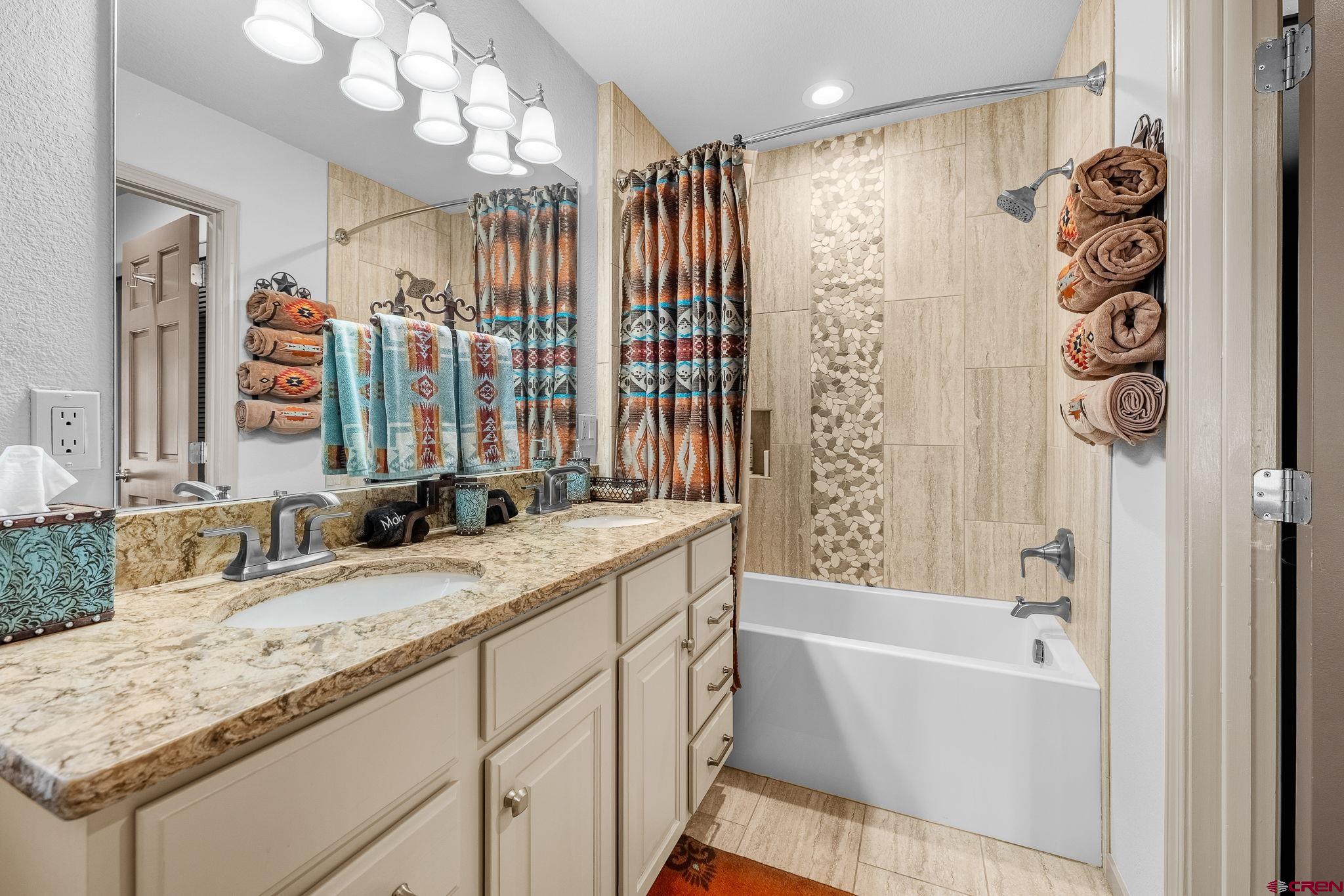 243 Cypress Court Durango, CO 81301 - Photo 25 of 42 a bathroom with a granite countertop sink a mirror a vanity and a bathtub
