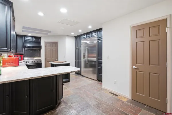 a room with kitchen island granite countertop a sink and a stove