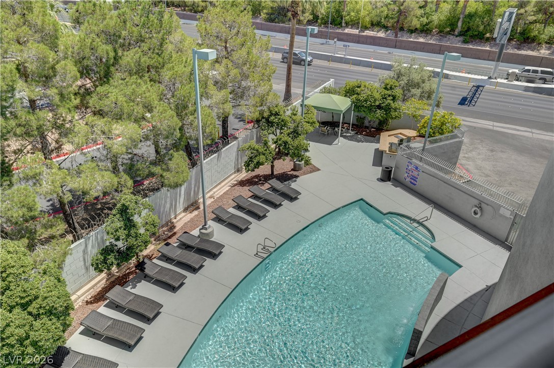 360 East Desert Inn Road, Unit 402 Las Vegas, NV 89109 - Photo 29 of 40 An inviting curved pool and surrounding lounging area offer a refreshing escape alongside convenient outdoor amenities.