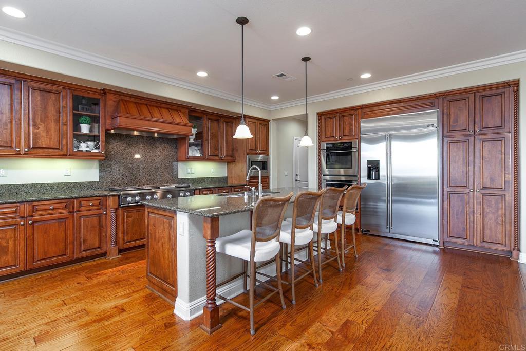 7231 Ocotillo Street Santee, CA 92071 - Photo 12 of 59 a kitchen with stainless steel appliances granite countertop a refrigerator a sink dishwasher a stove and a dining table with wooden floor
