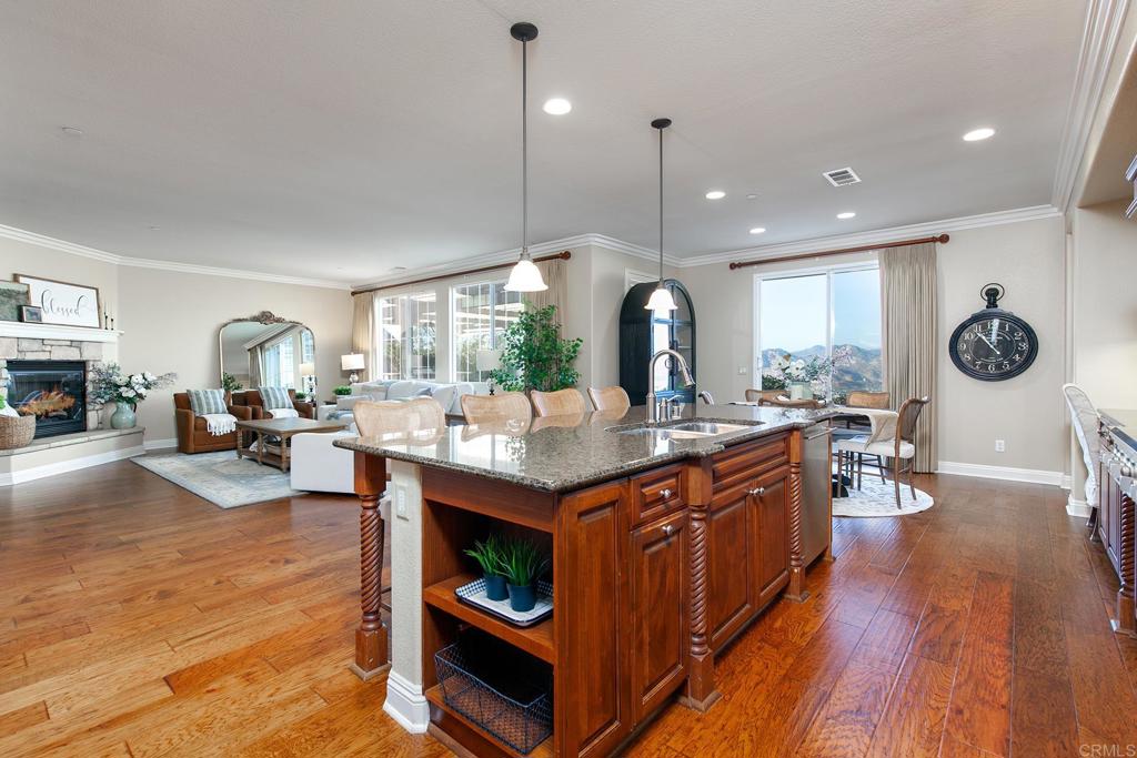 7231 Ocotillo Street Santee, CA 92071 - Photo 14 of 59 a kitchen with stainless steel appliances granite countertop a stove a refrigerator a sink dishwasher with a dining table and chairs with wooden floor