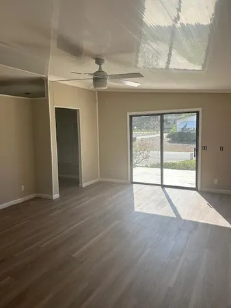 an empty room with wooden floor fan and windows