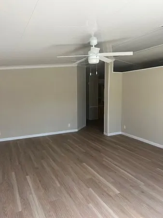 an empty room with wooden floor and chandelier fan
